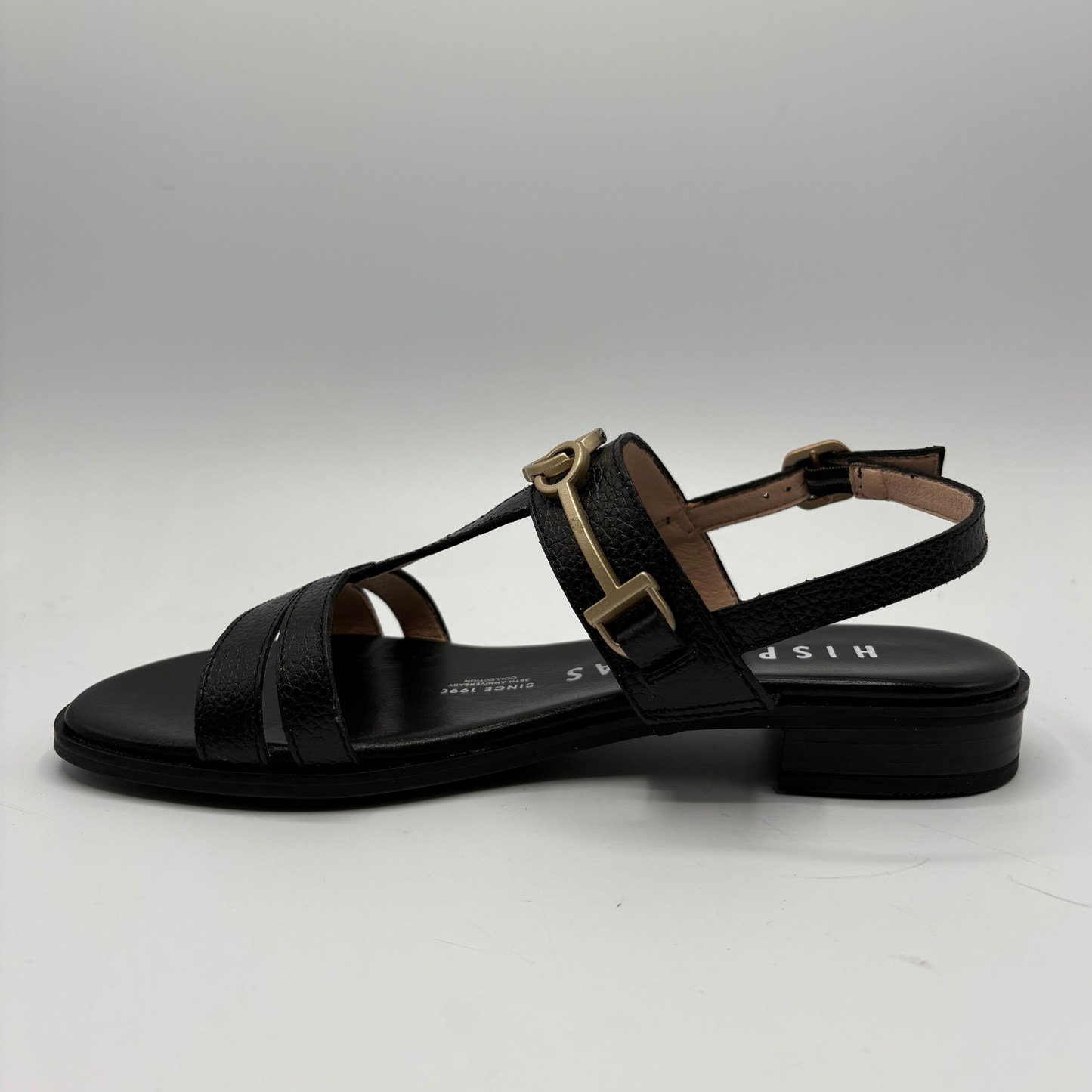 Black sandal with brown buckle on a white background