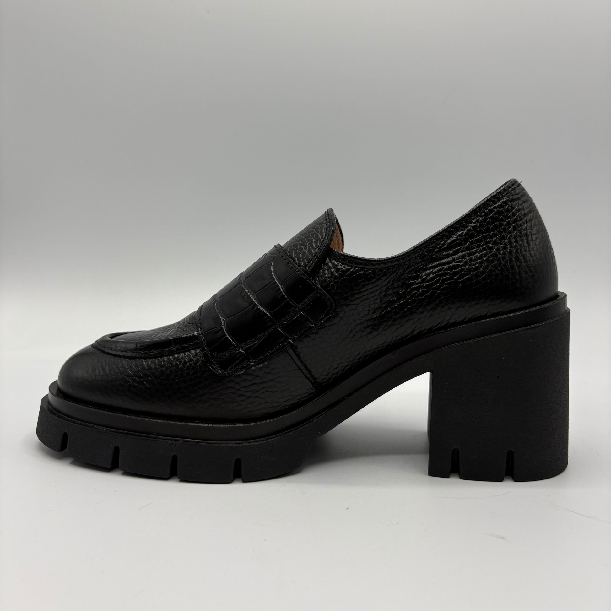 Left facing view of a black leather loafer with a chunky heel.