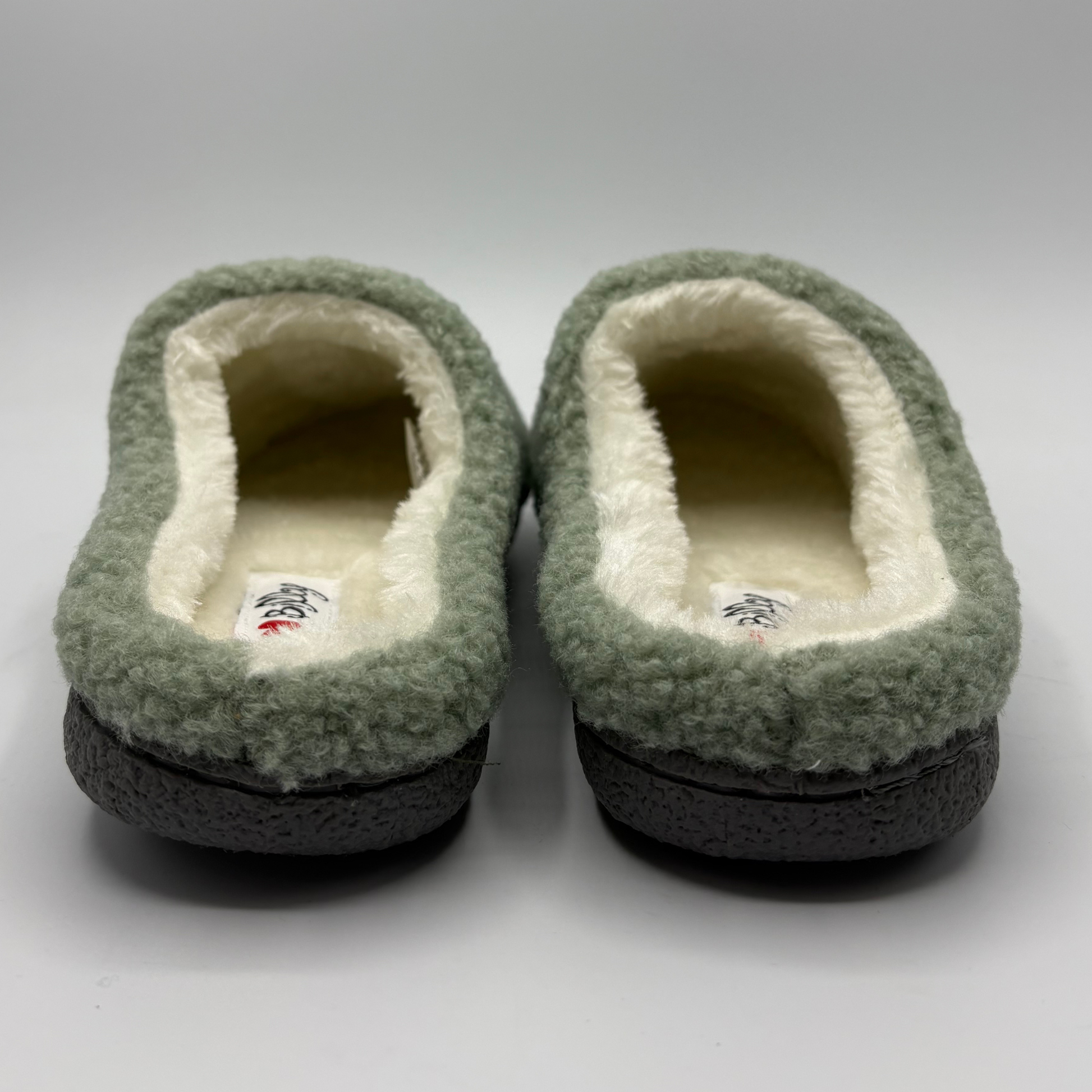 Back view of a plush fleece slip-on slippers in sage green, featuring a cream sherpa lining