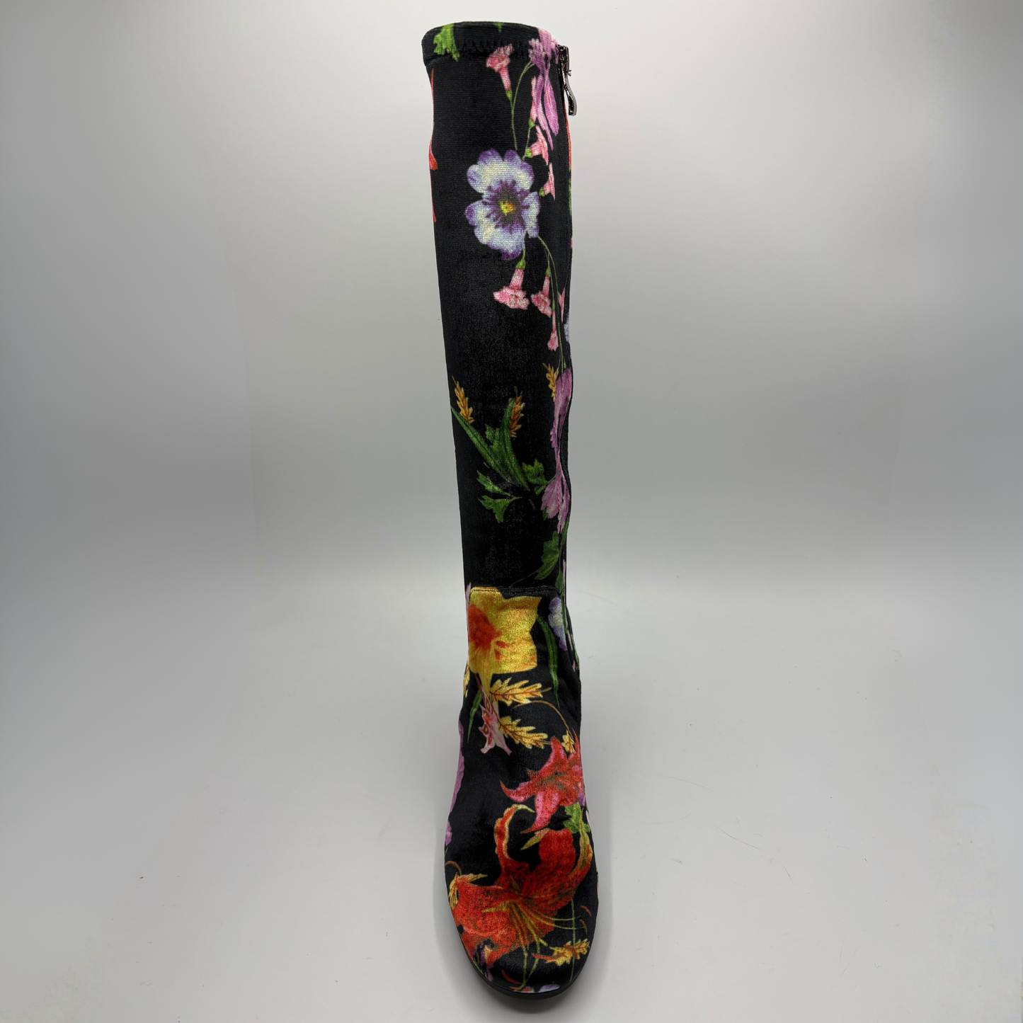 A single knee-high boot with a black base and a vibrant, multicolored floral print featuring pink, red, purple, and green flowers, shown against a neutral gray background.
