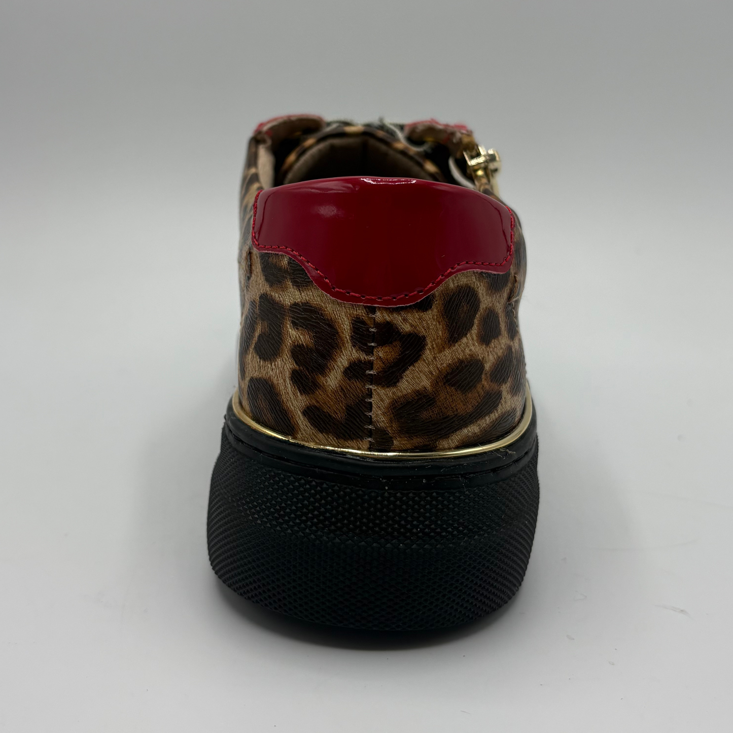 A low-top platform sneaker featuring a brown and black leopard print upper, red patent leather side panels, a gold zipper, and a thick black platform sole.