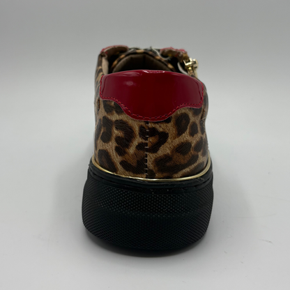 A low-top platform sneaker featuring a brown and black leopard print upper, red patent leather side panels, a gold zipper, and a thick black platform sole.