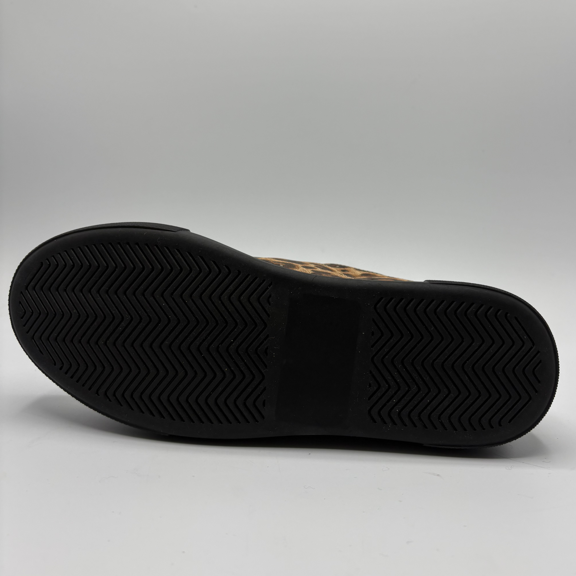 A low-top platform sneaker featuring a brown and black leopard print upper, red patent leather side panels, a gold zipper, and a thick black platform sole.