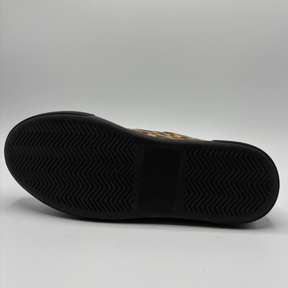 A low-top platform sneaker featuring a brown and black leopard print upper, red patent leather side panels, a gold zipper, and a thick black platform sole.
