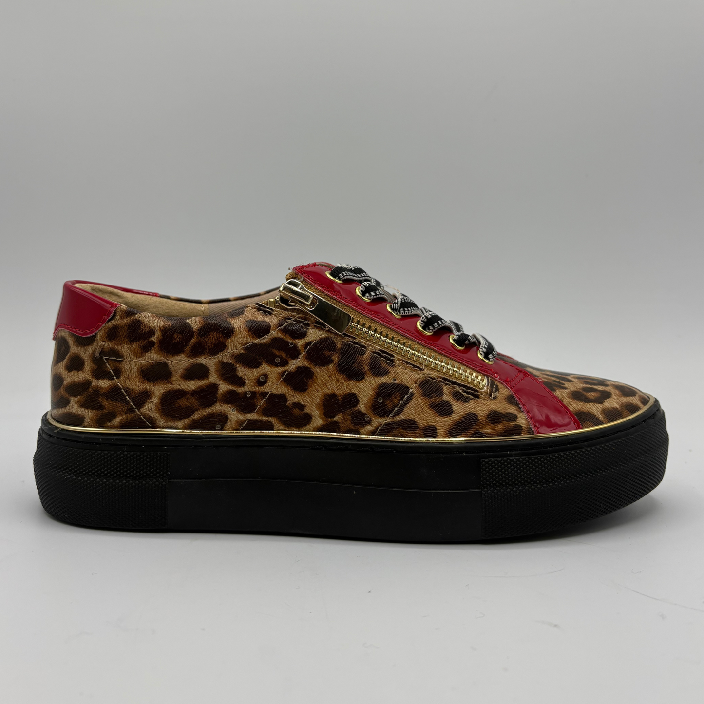 A low-top platform sneaker featuring a brown and black leopard print upper, red patent leather side panels, a gold zipper, and a thick black platform sole.