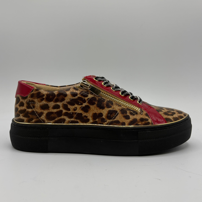 A low-top platform sneaker featuring a brown and black leopard print upper, red patent leather side panels, a gold zipper, and a thick black platform sole.