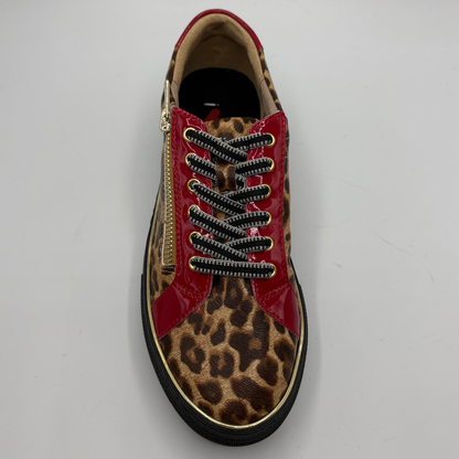 A single low-top sneaker shown from a top-down view on a light gray background. The shoe features a leopard print pattern on the toe and quarter panels, glossy red patent leather side panels, black and white patterned laces, a gold zipper on the side, and a black sole with a thin gold trim.