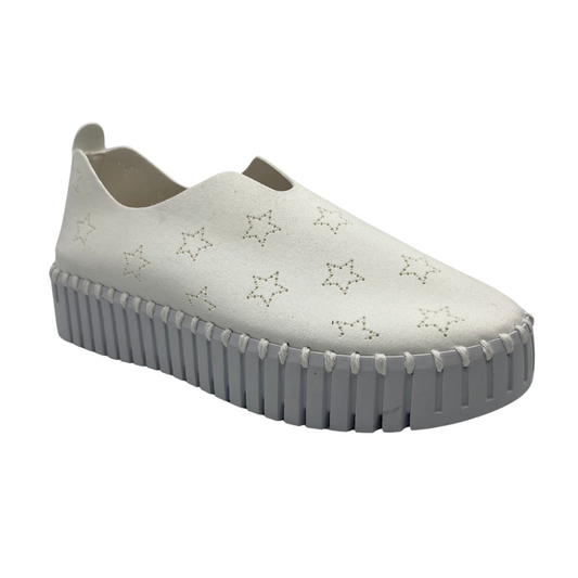 45 degree angled view of white slip on sneakers with small star cutouts on upper. White rubber platform sole.