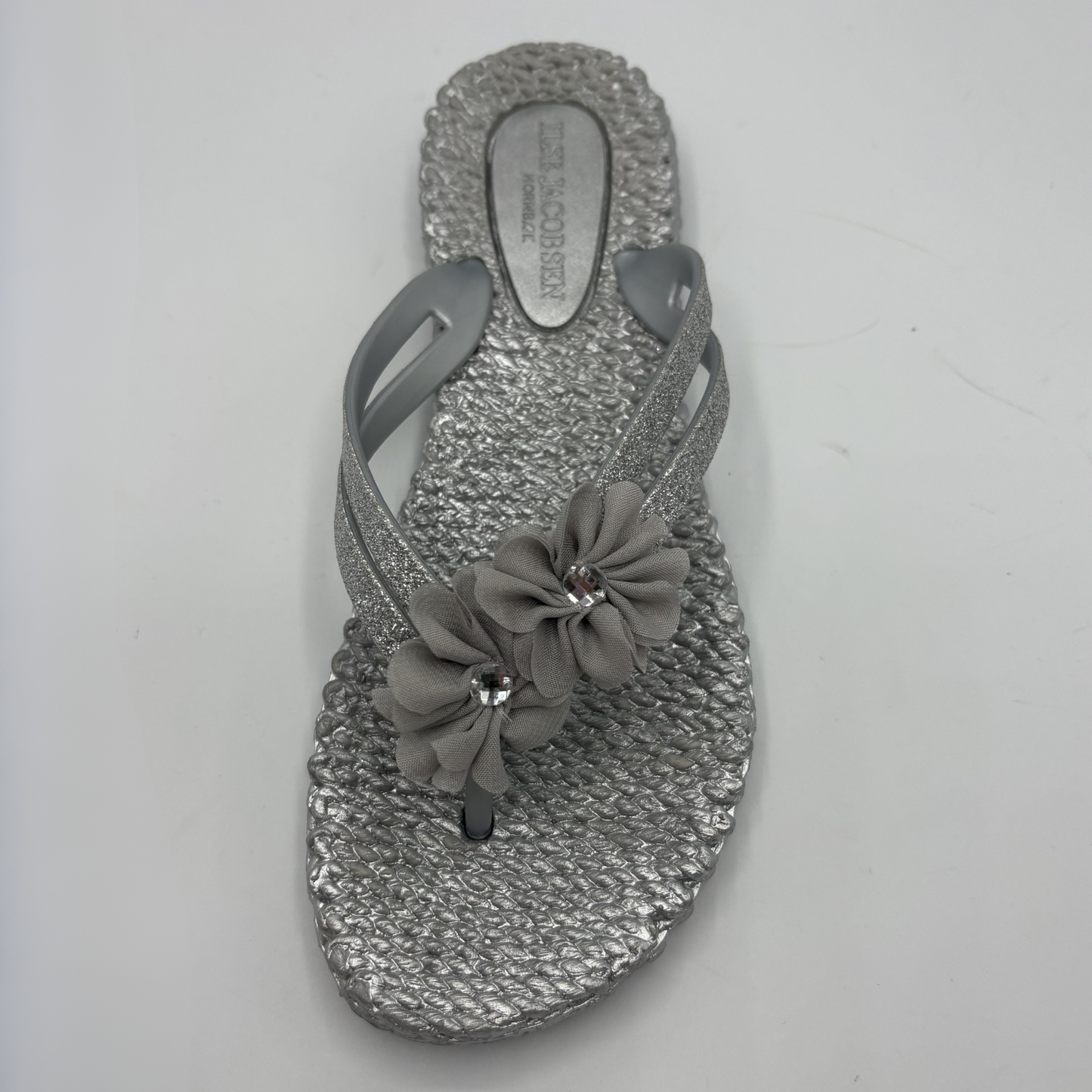 Top view of a silver flip flop with flower accents
