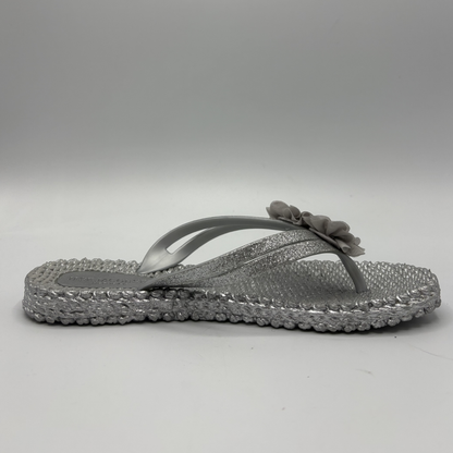 Right facing view of a silver flip flop with flower accents