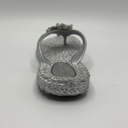 Back view of a silver flip flop with flower accents
