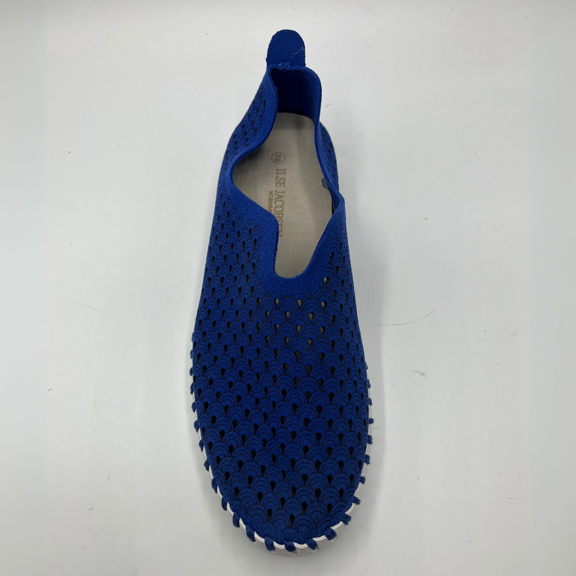 Top view of blue slip on shoe with an intricate laser cut upper and white rubber outsole.