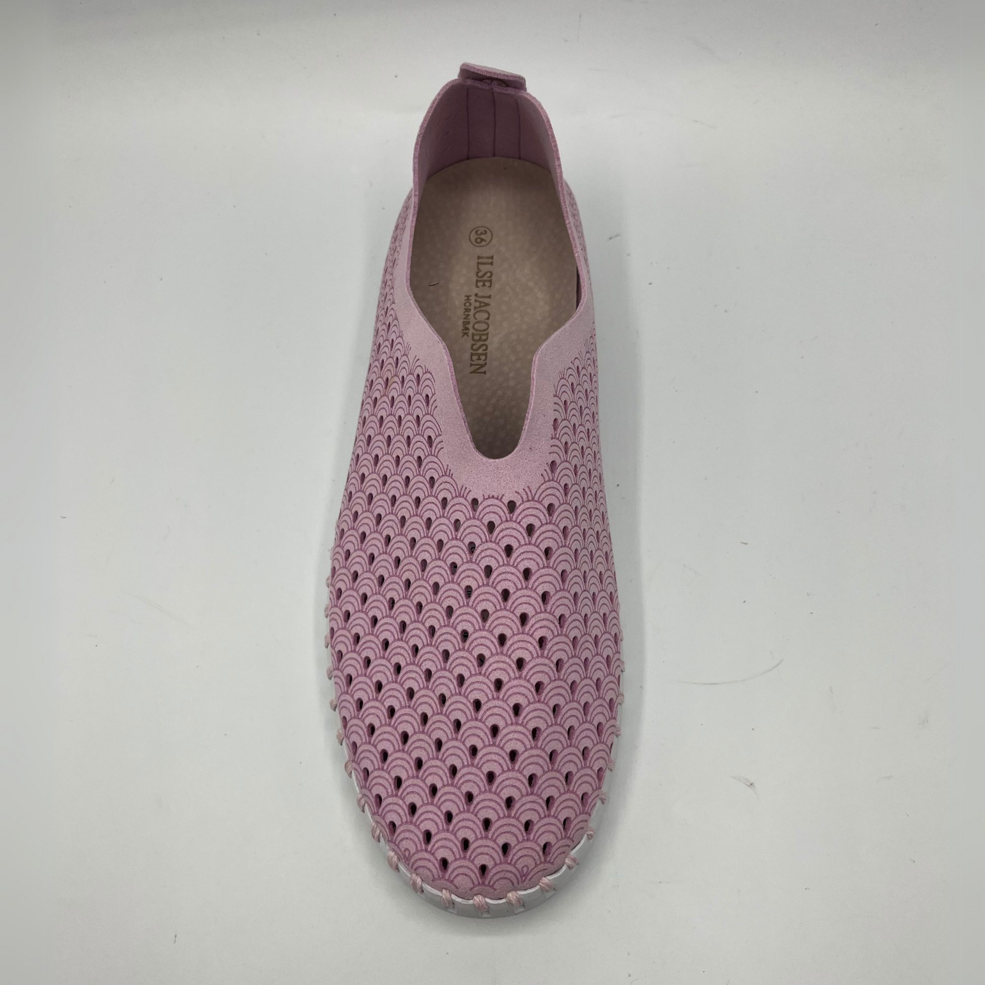 Top view of bubble pink slip on shoe with an intricate laser cut upper and white rubber outsole.