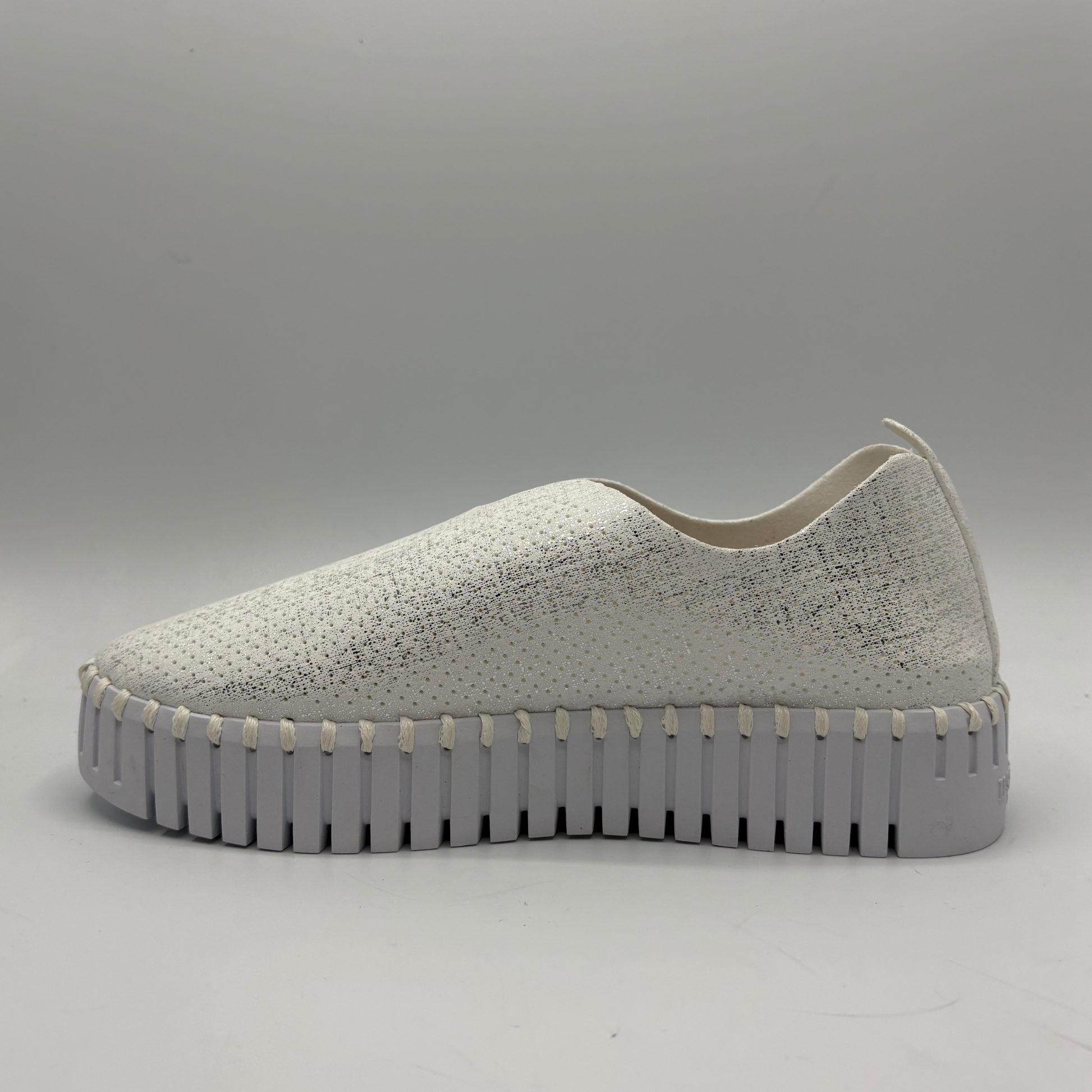 White slip-on sneaker with a thick gray sole on a light gray background