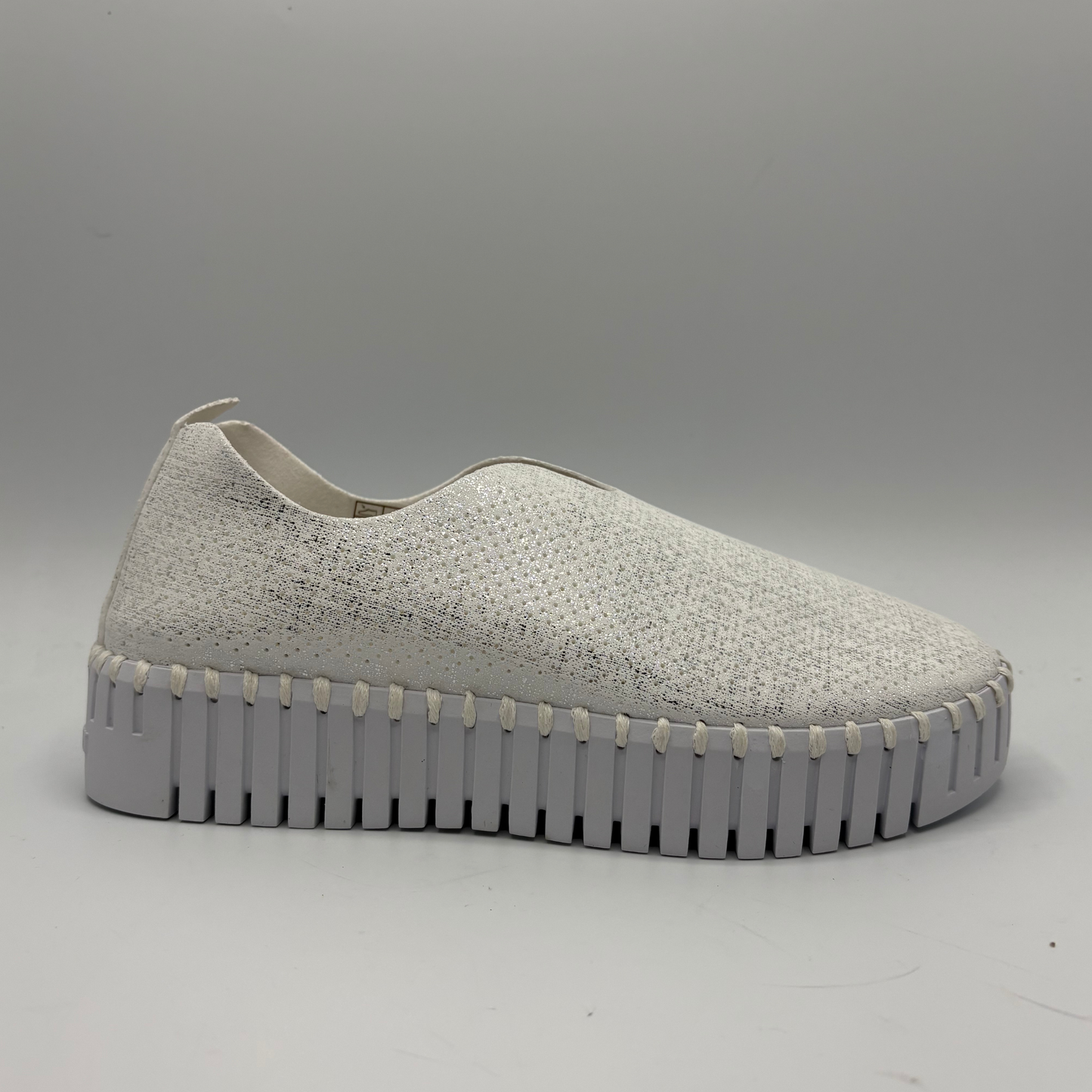 White slip-on sneaker with a thick sole on a gray background