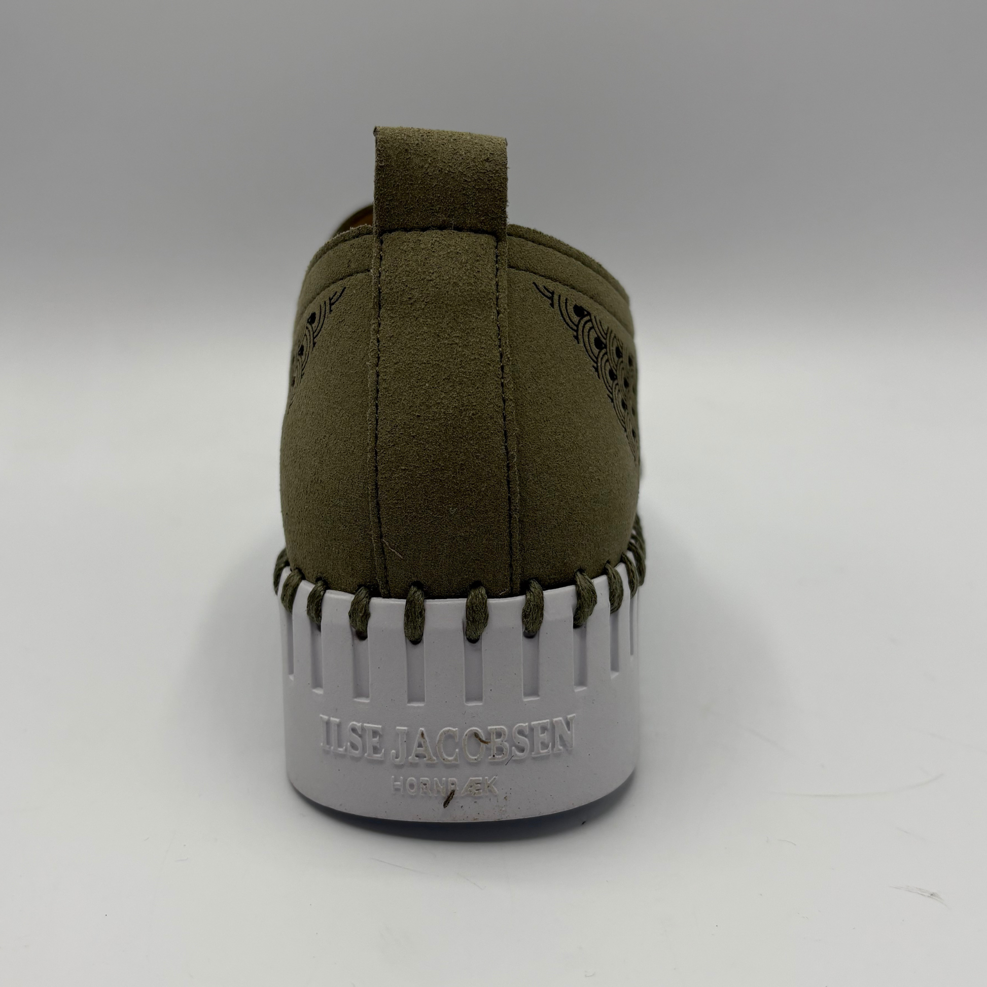 Green sneaker with white sole on a gray background