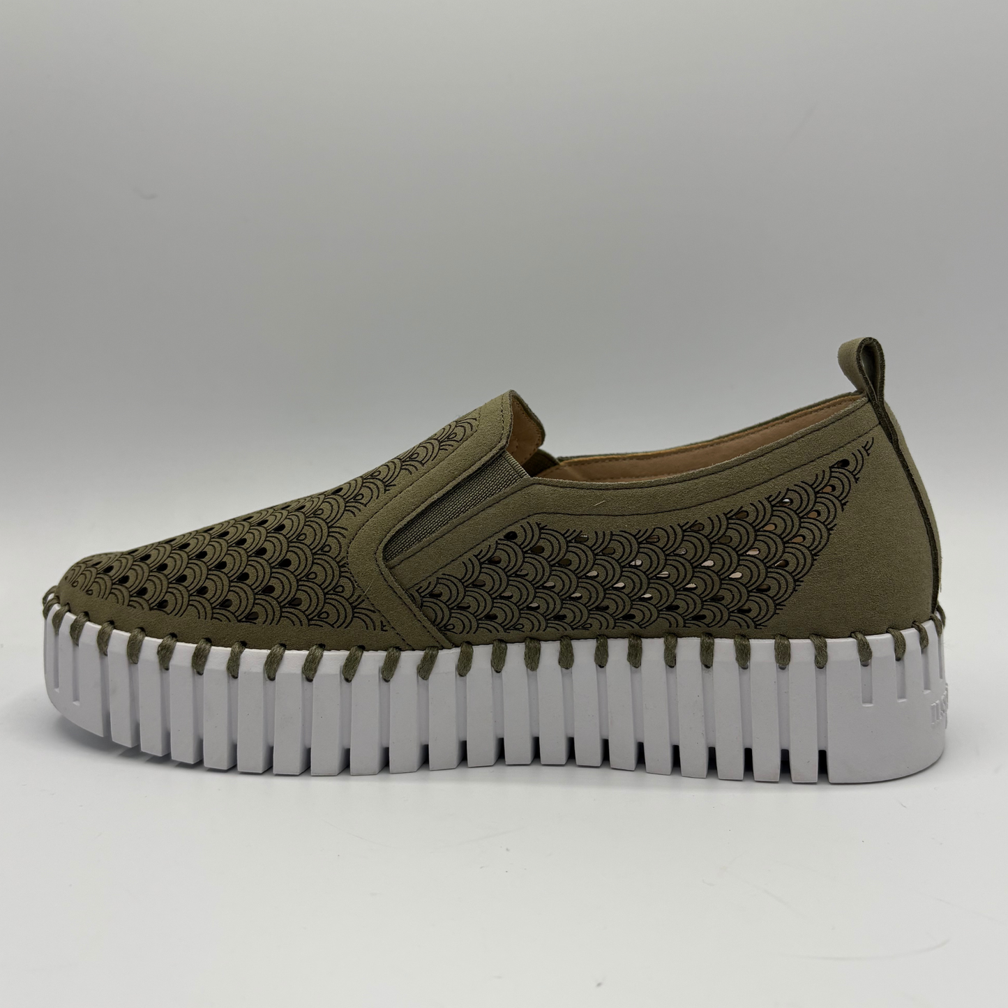 Green slip-on shoe with a thick white sole on a gray background
