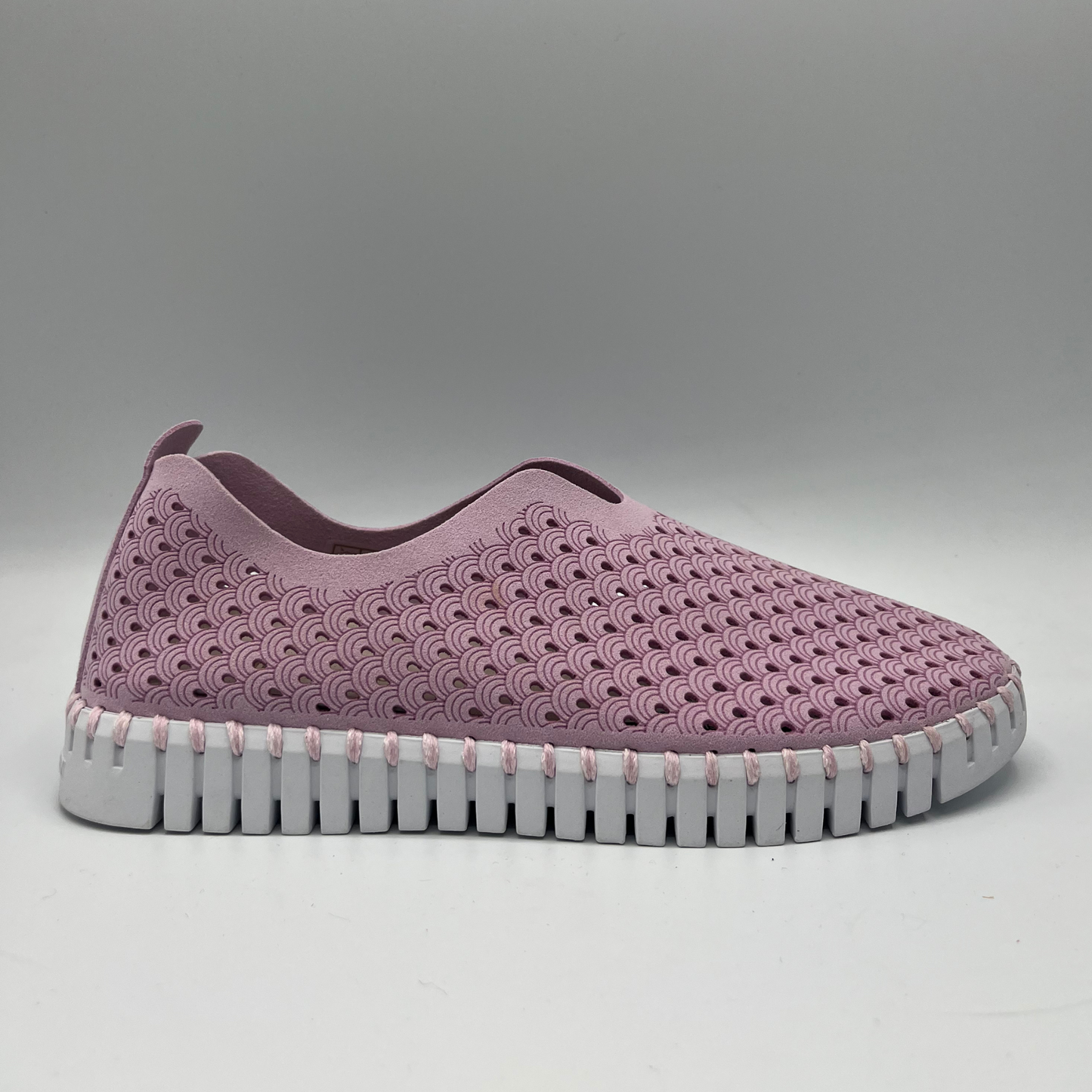 Right facing view of bubble pink slip on shoe with an intricate laser cut upper and white rubber outsole.