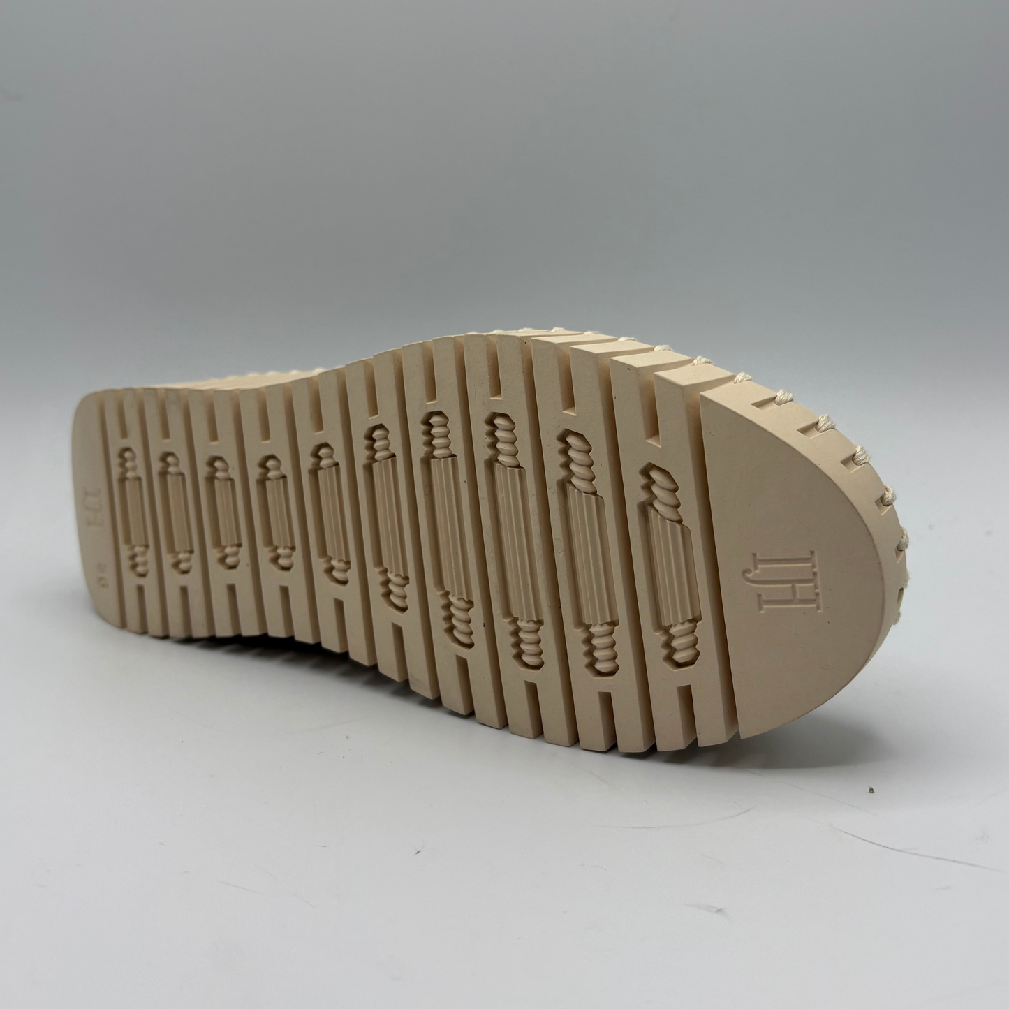 Beige shoe sole with tread pattern on a gray background