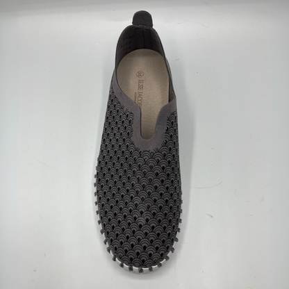 Top  view of grey smoked pearl slip on shoe with an intricate laser cut upper and white rubber outsole.