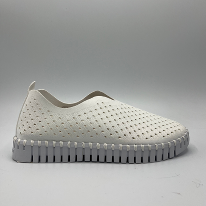 Right facing view of white slip on shoe with an intricate laser cut upper and white rubber outsole.