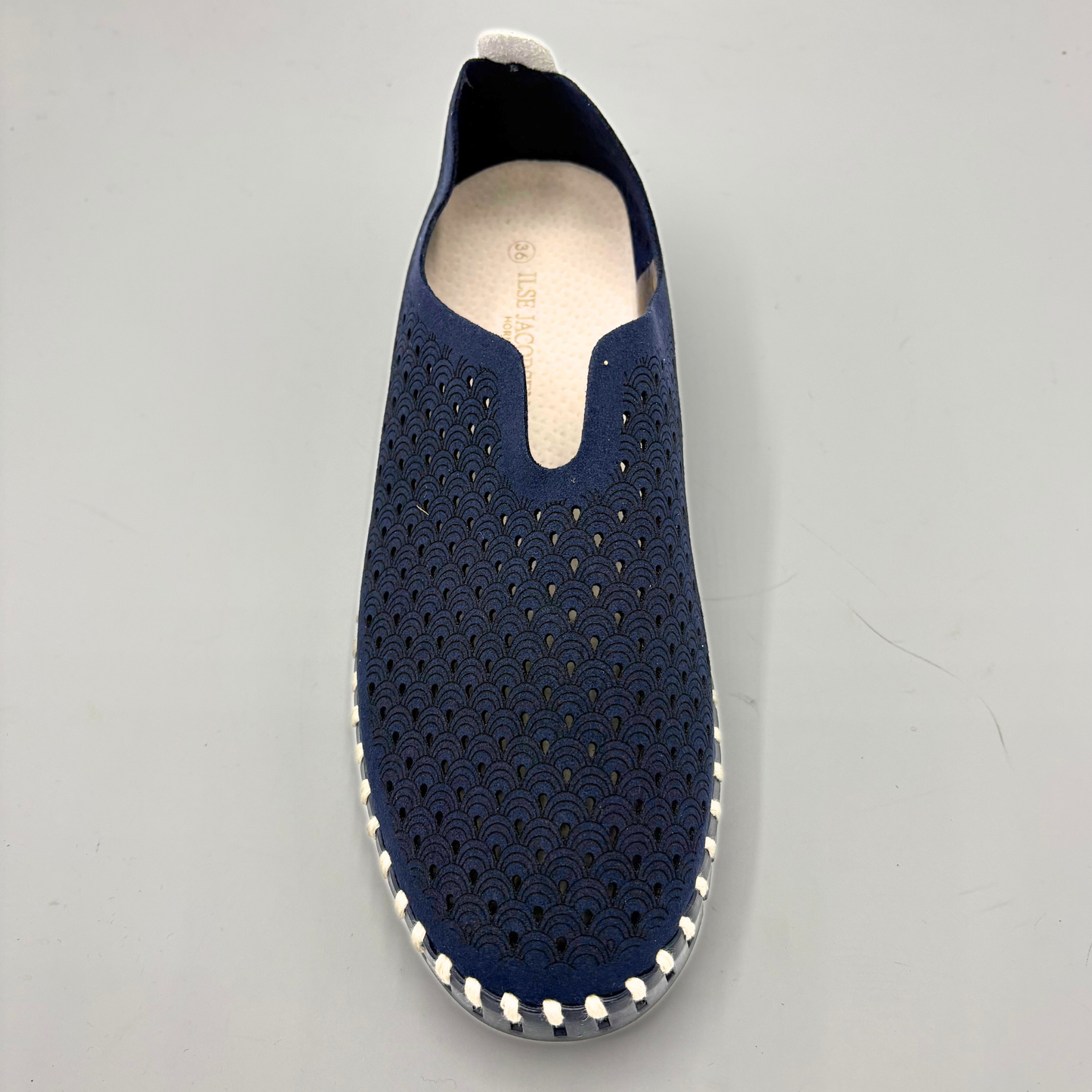 Navy slip-on shoe with perforated design on a gray background