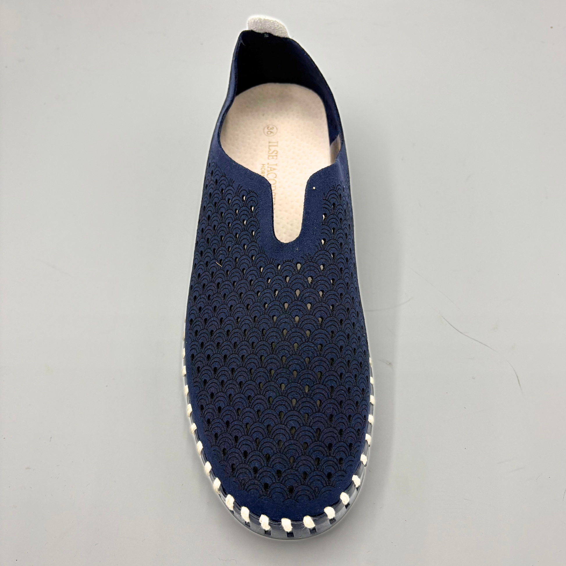 Navy slip-on shoe with perforated design on a gray background