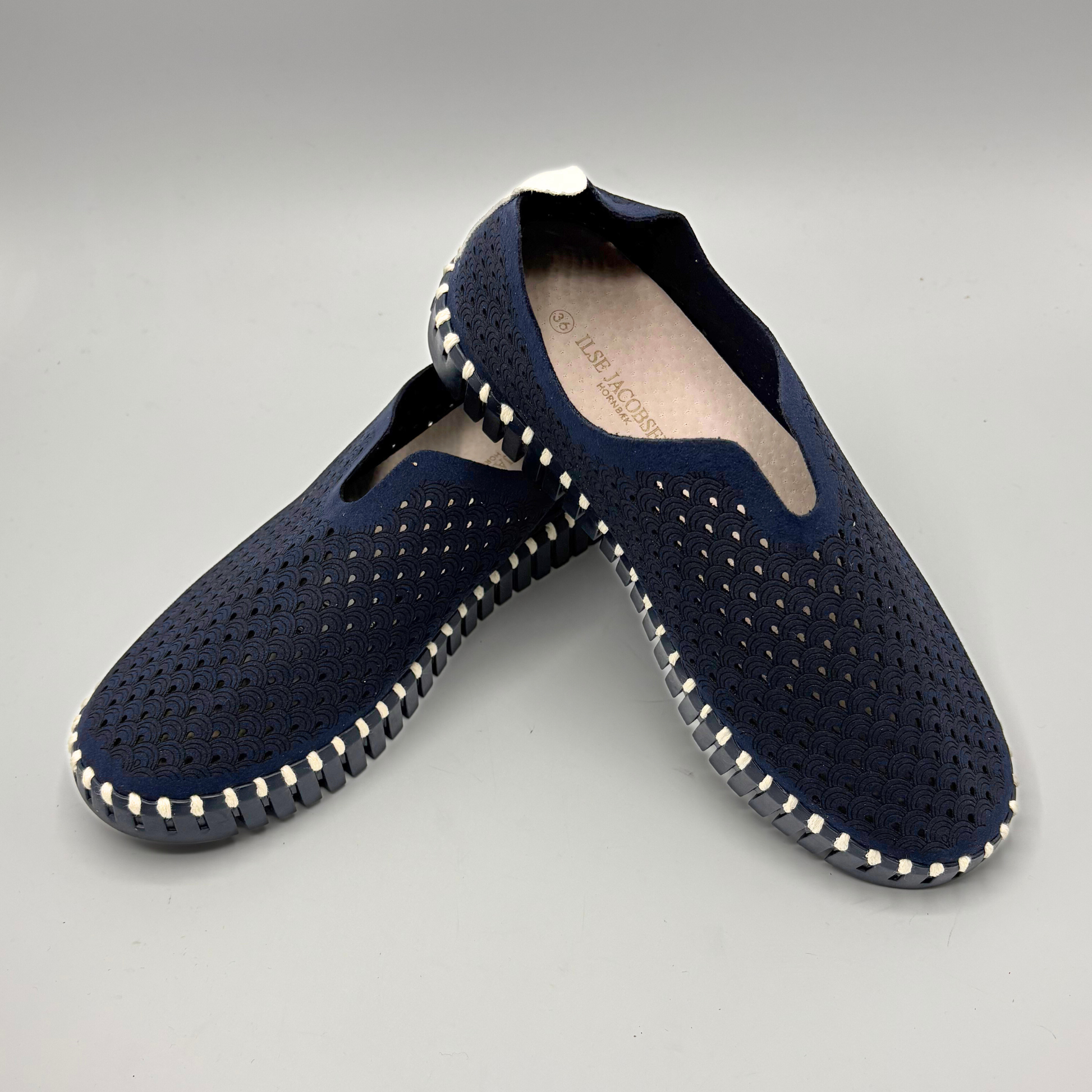 Pair of navy blue shoes with white stitching on a gray background