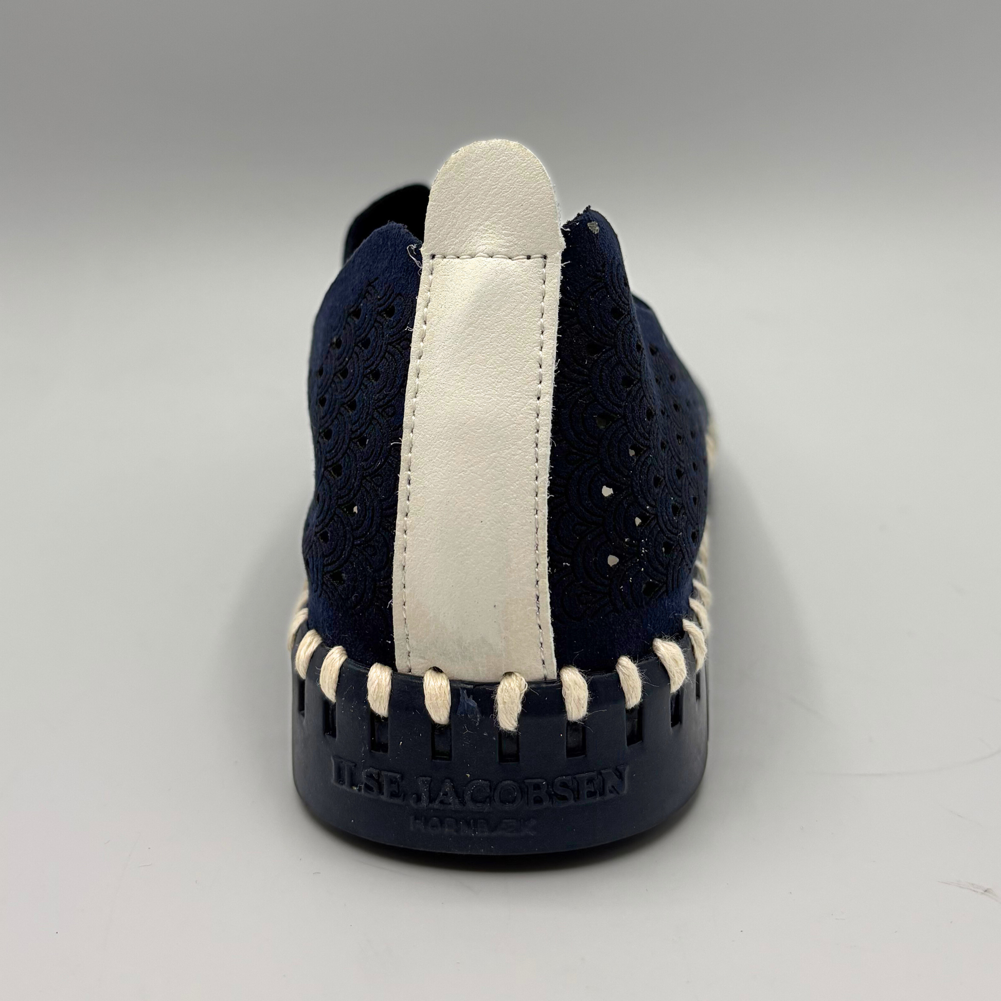 Navy slip-on shoe with white sole on a gray background
