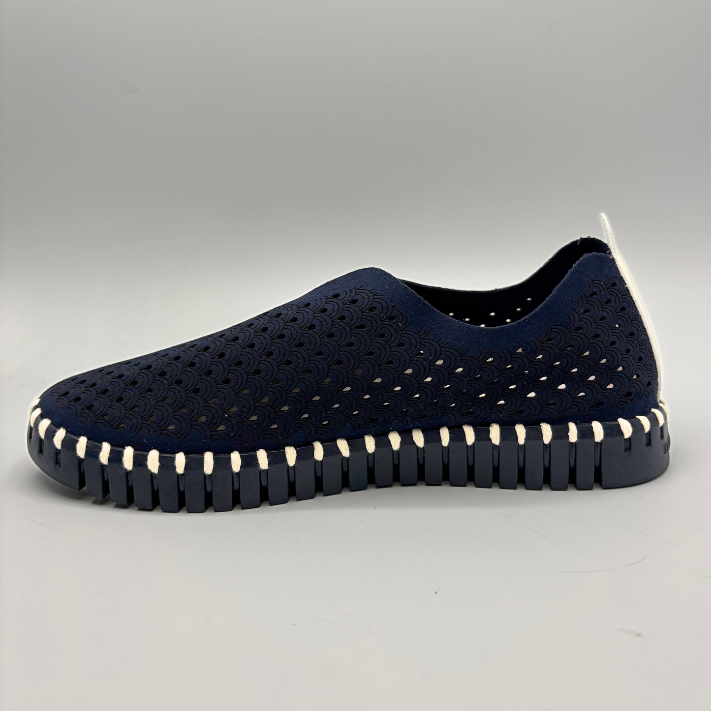 Navy slip-on shoe with white sole on a gray background