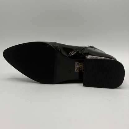 A black patent leather pointed-toe boot shown from the sole side, featuring a glossy finish, a low block heel, and a textured rubber outsole.