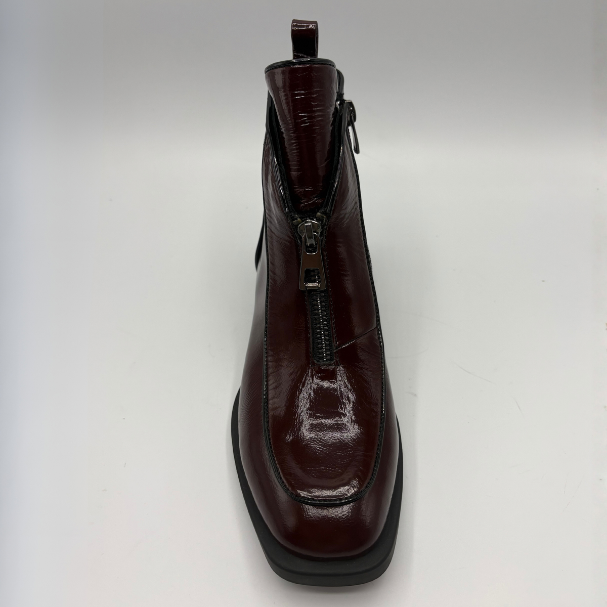 Front view of a deep red patent leather short boot with a front zipper closure