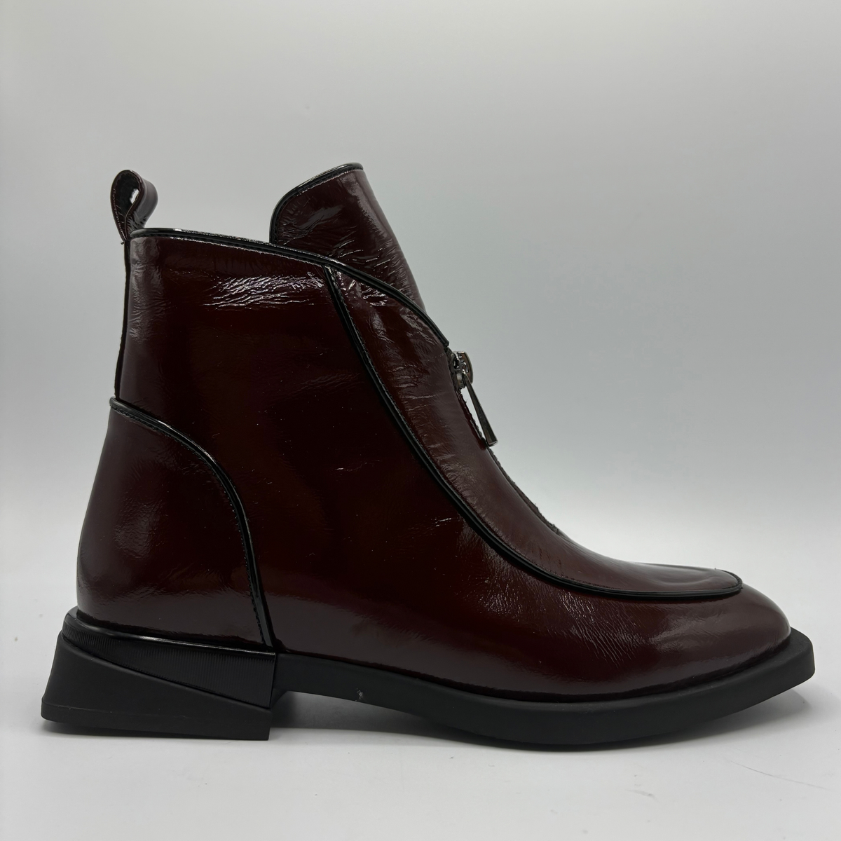 Right facing view of a deep red patent leather short boot with a front and side zipper