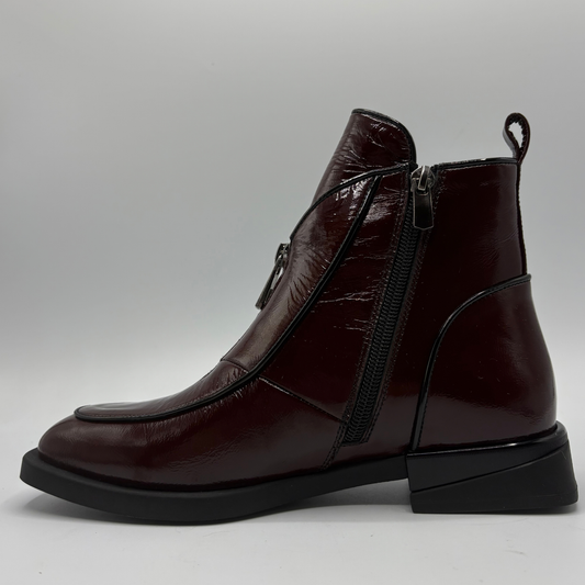 Left facing view of a deep red patent leather short boot with a side and front zipper