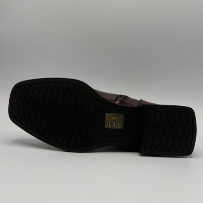 Bottom view of a deep red patent leather short boot with a black rubber outsole