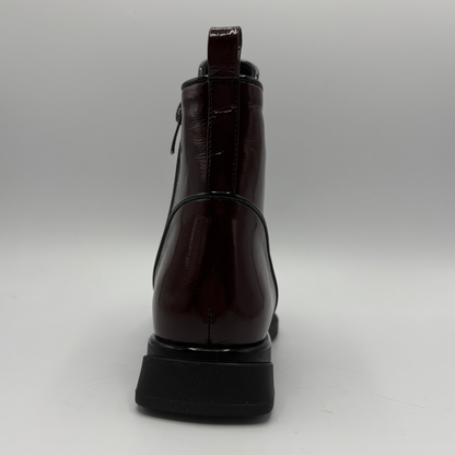 Back view of a deep red patent leather short boot with a pull on heel tab