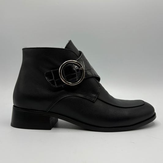Right facing view of a black leather ankle boot with a croc textured strap and a circular buckle