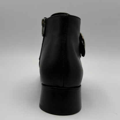 Back view of a black leather ankle boot with a croc textured strap and a circular buckle