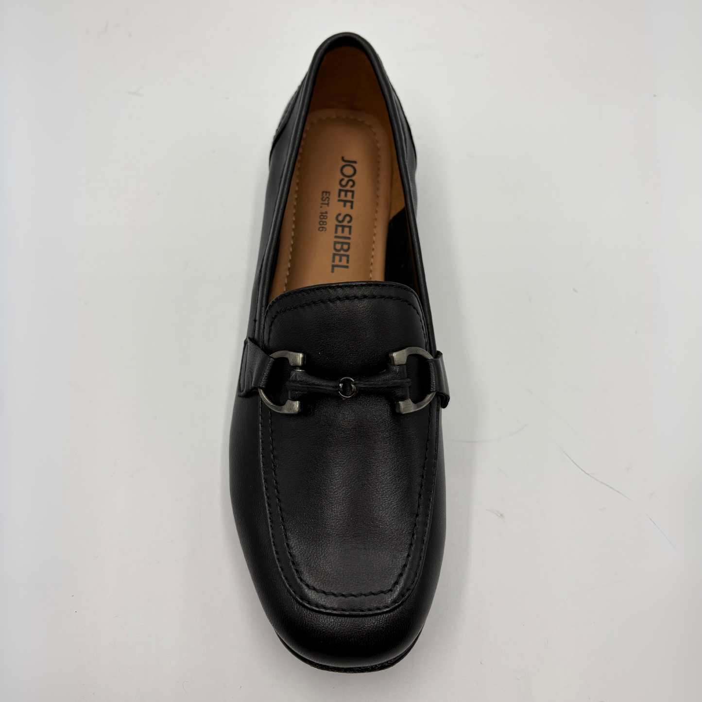 Black loafer shoe with a visible brand name on a light gray background