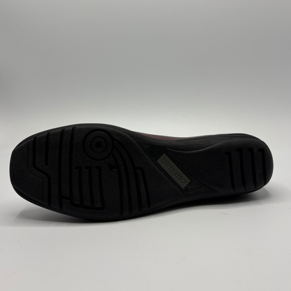 The black rubber outsole of a shoe, showing tread patterns and a small 'D'NUEVO' brand tag, photographed against a neutral gray studio background.