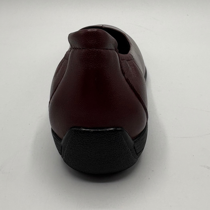 A single slip-on shoe shown from the back, featuring a dark burgundy leather upper and a black textured sole, set against a plain light gray background.