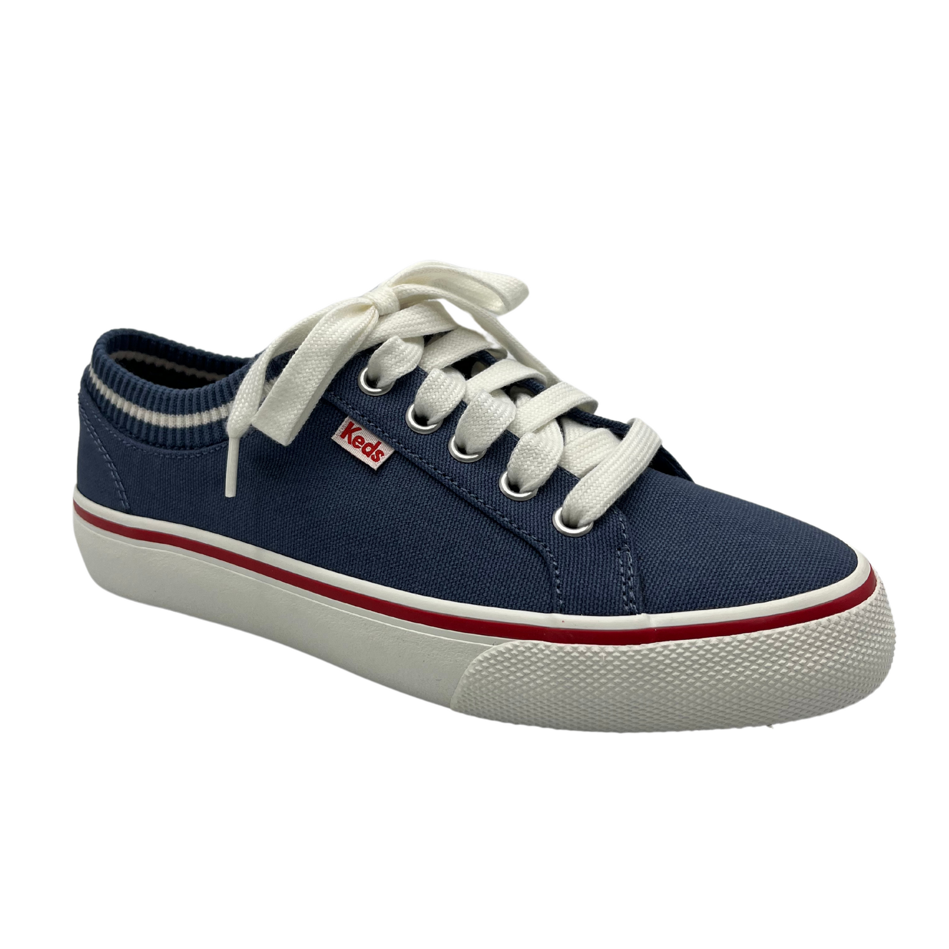 45 degree angled view of navy canvas shoes with sock opening, white laces and rubber outsole