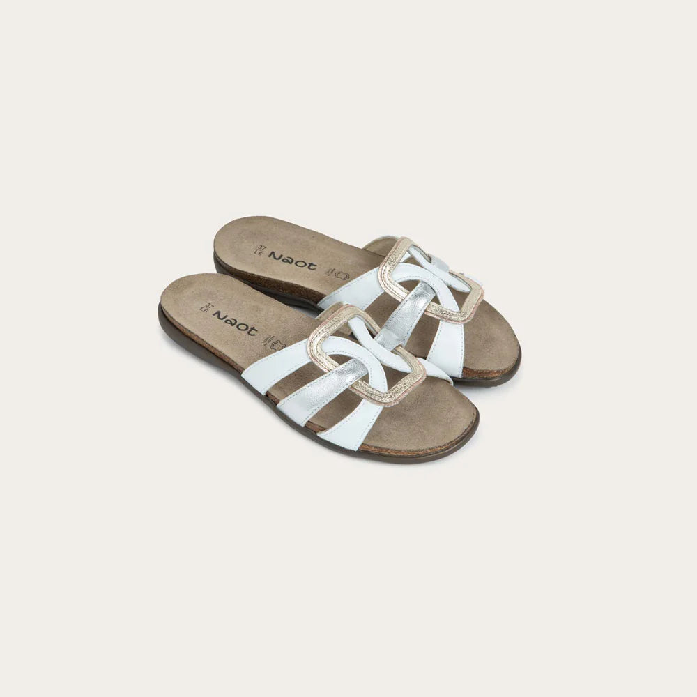 Pair of white sandals with brown soles on a light beige background