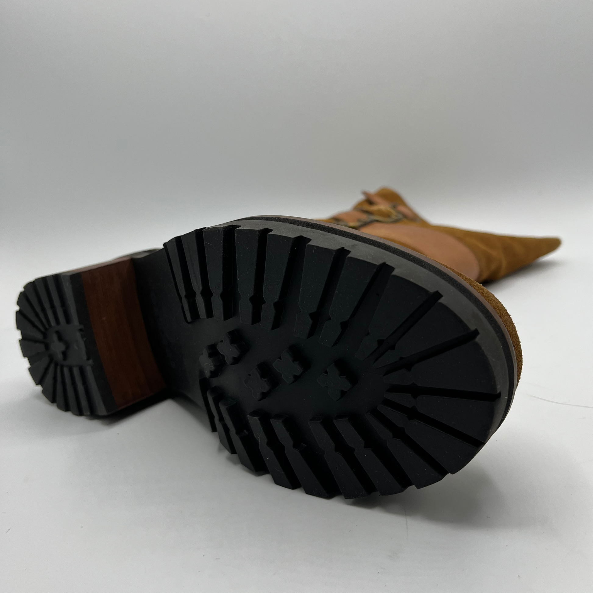 Brown suede boot with black sole on a white background