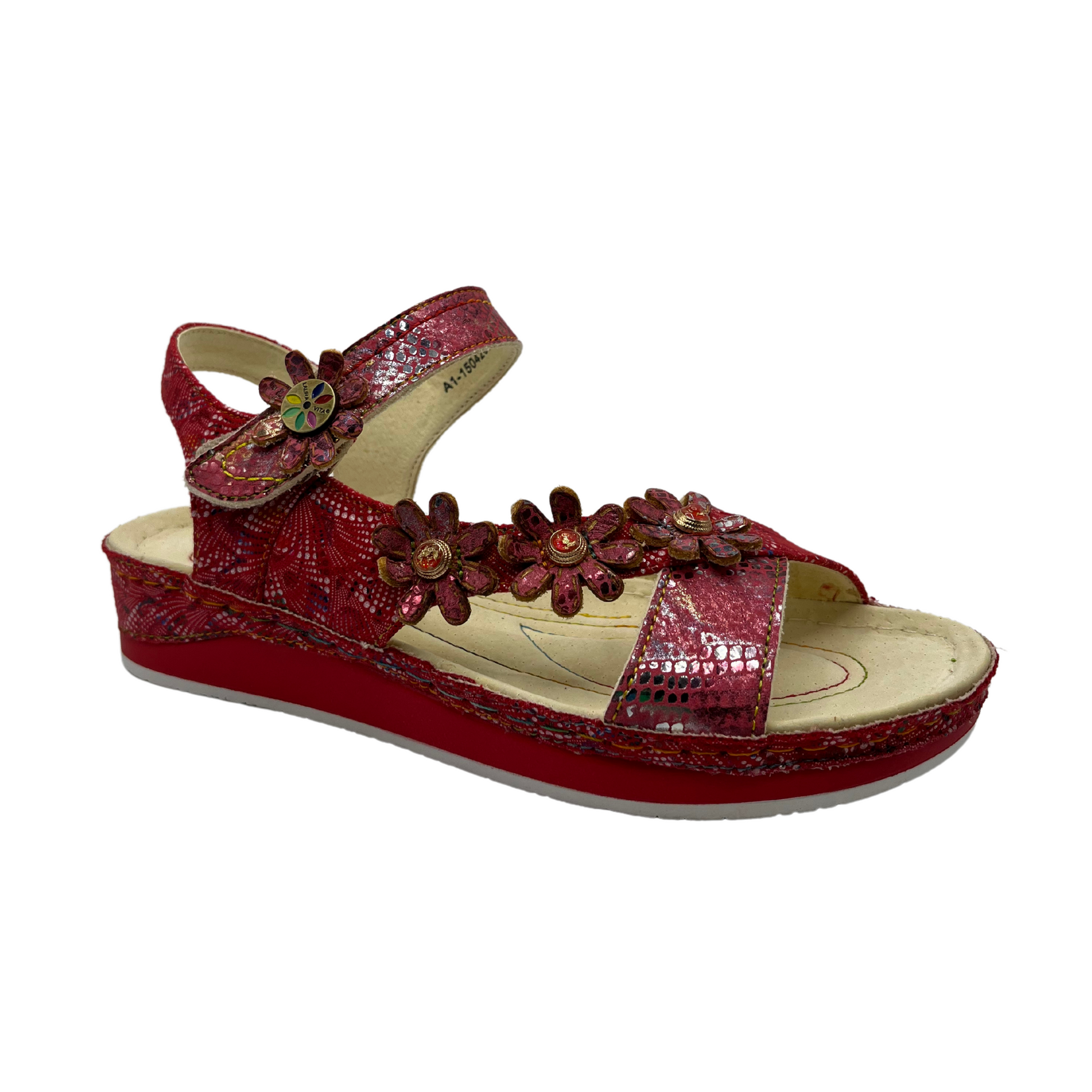 45 degree angled view of a red leather sandal with flower details and velcro ankle strap