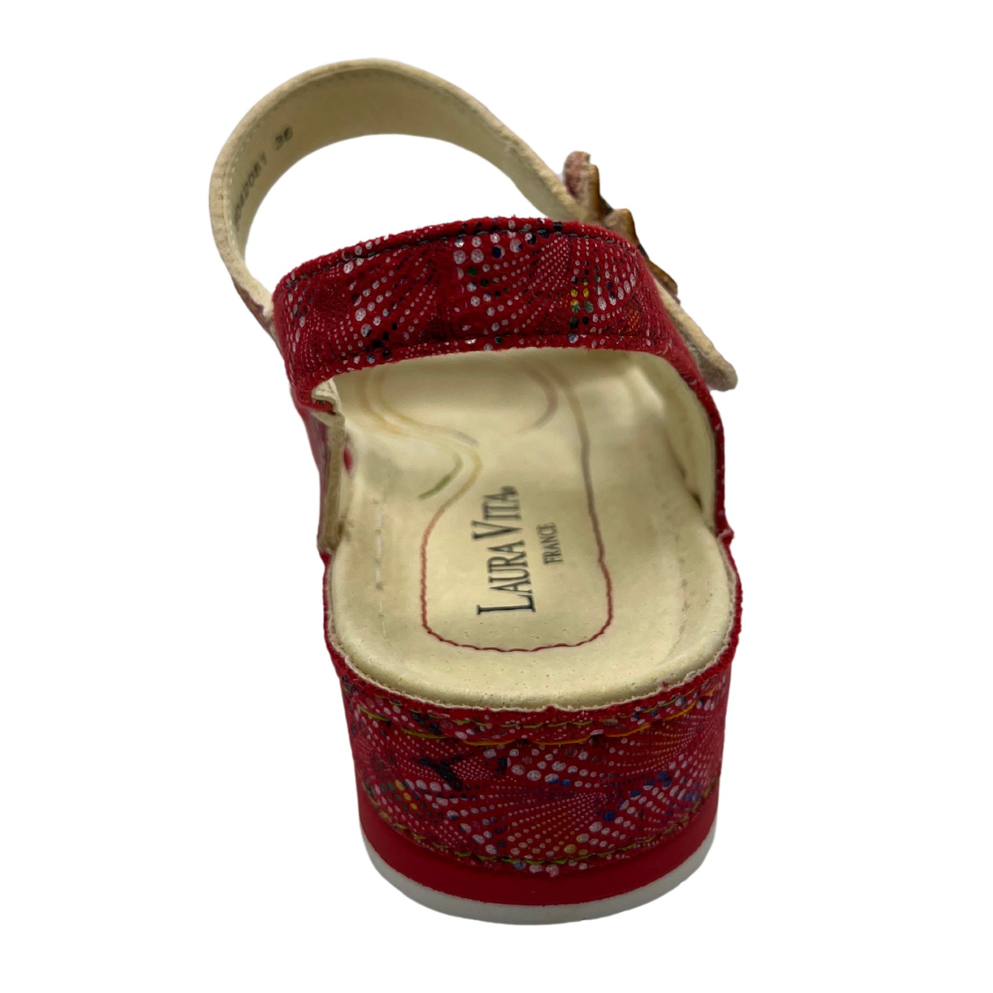Back view of a red leather sandal with flower details and velcro ankle strap