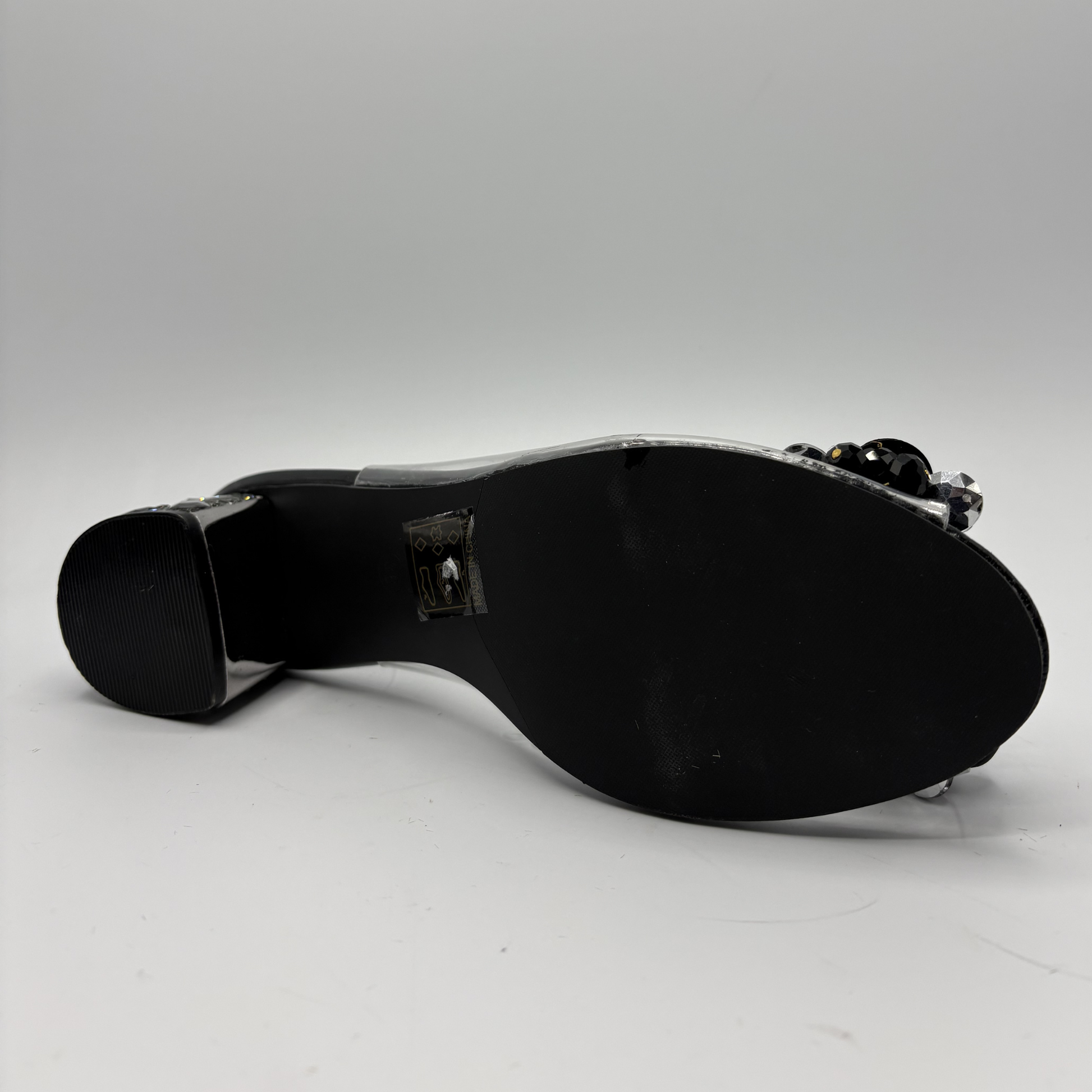 High heeled shoe with clear upper and jewelled heel on a gray background