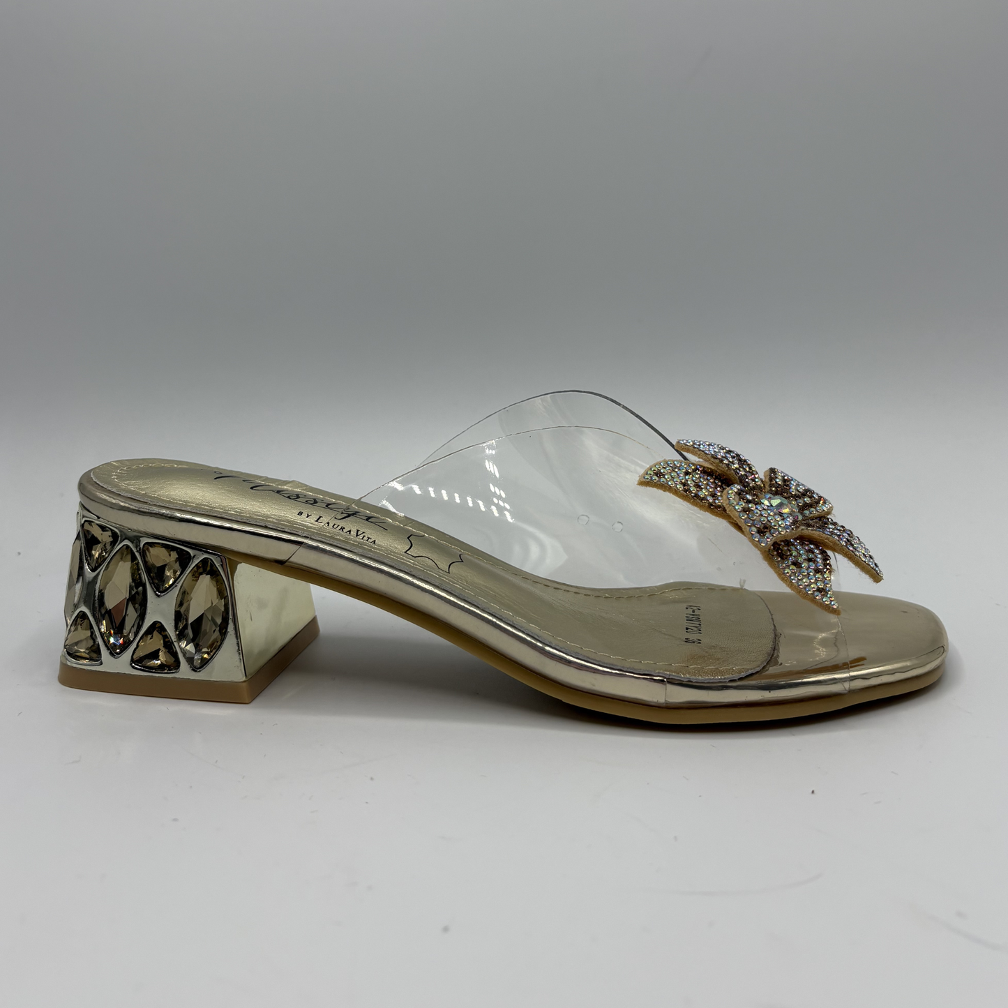Clear sandal with decorative strap and low heel on a gray background