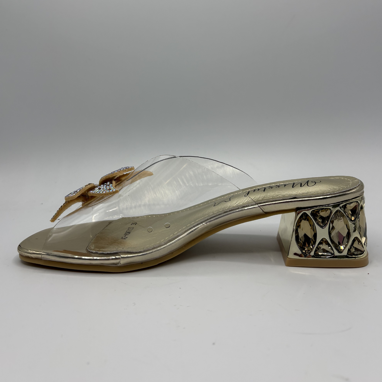 Clear sandal with decorative strap and low heel on a gray background