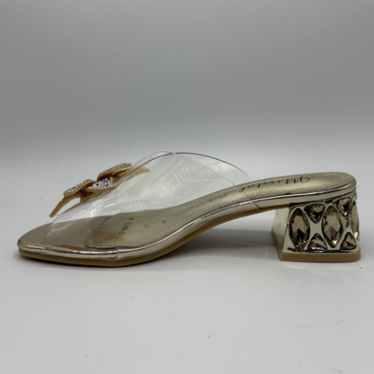 Clear sandal with decorative strap and low heel on a gray background